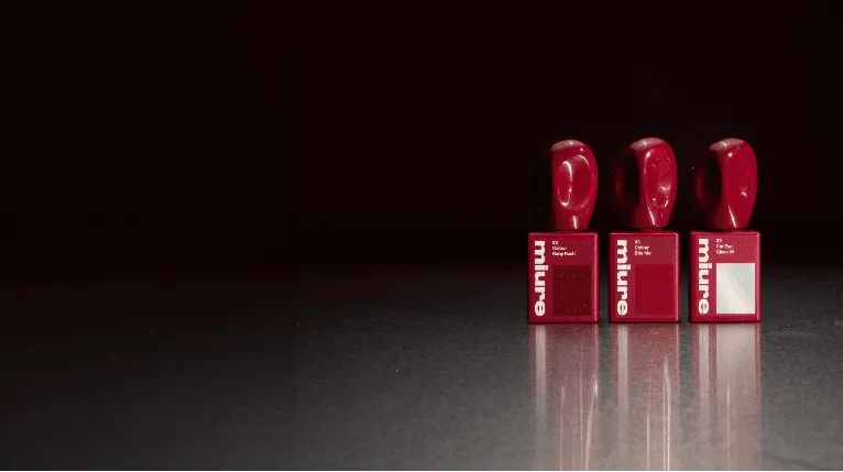 Three red miure-branded dispensers with rounded tops stand in a row on a reflective surface.